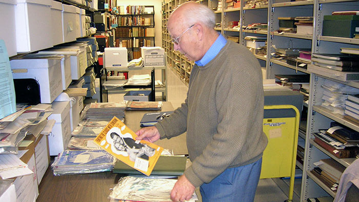 A person in the Special Collections stacks, at a table looking at an old magazine